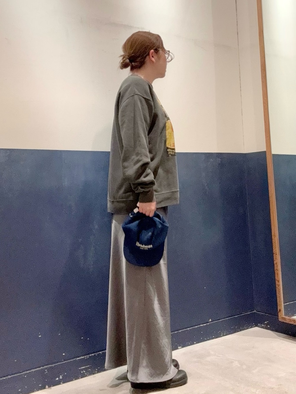 グレー系のスカート、ホワイト系のTシャツ/カットソー、ブラック系のスウェットを着用したレディースの秋コーディネートの2枚目の写真