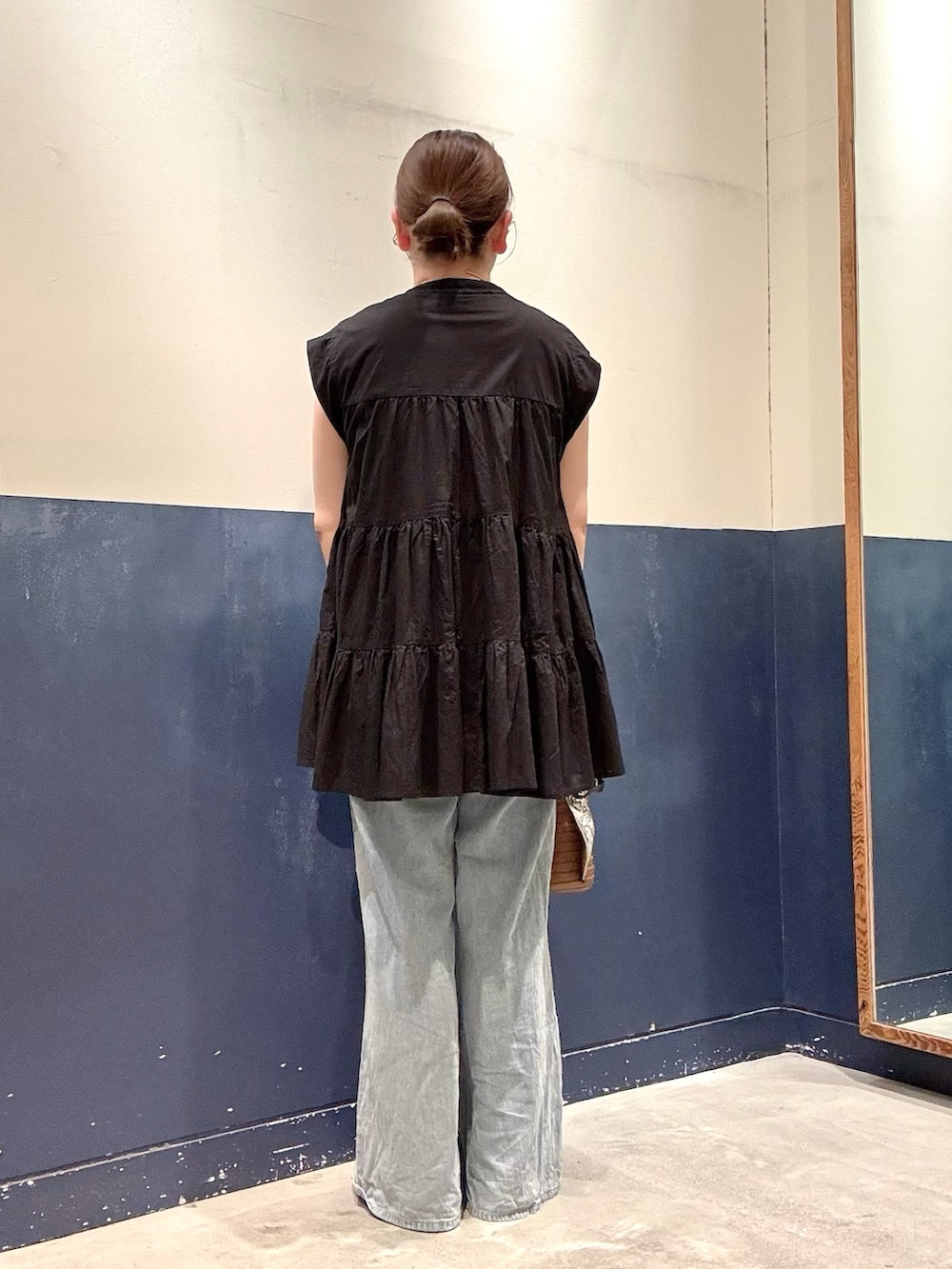 ブラック系のパンプス、ブルー系のデニムパンツ、ブラウン系のトートバッグを着用したレディースの夏コーディネートの3枚目の写真