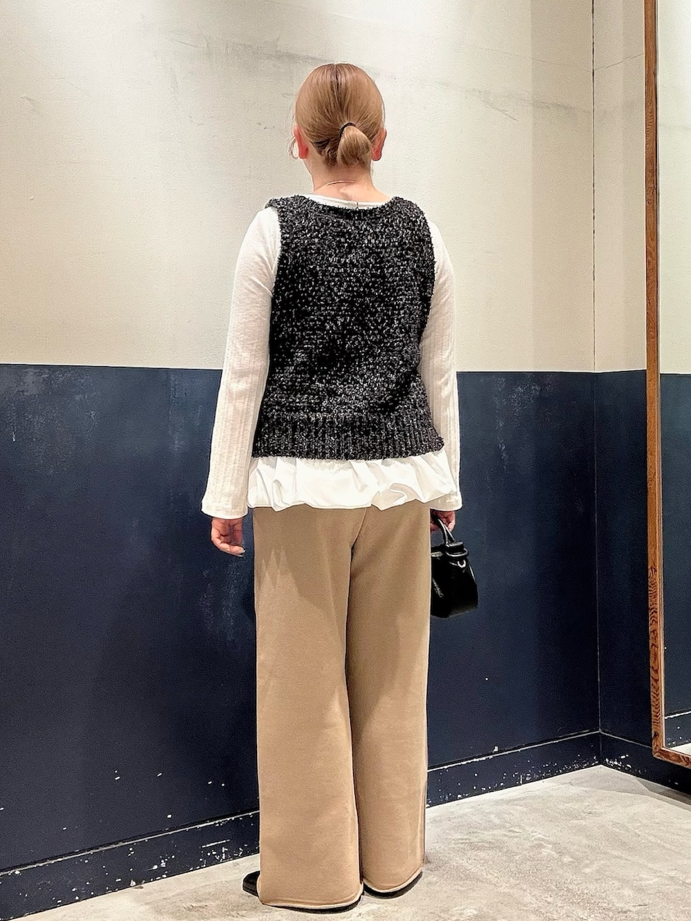 ホワイト系のTシャツ/カットソー、ブラック系のベスト、ブラック系のショルダーバッグを着用したレディースの冬コーディネートの3枚目の写真