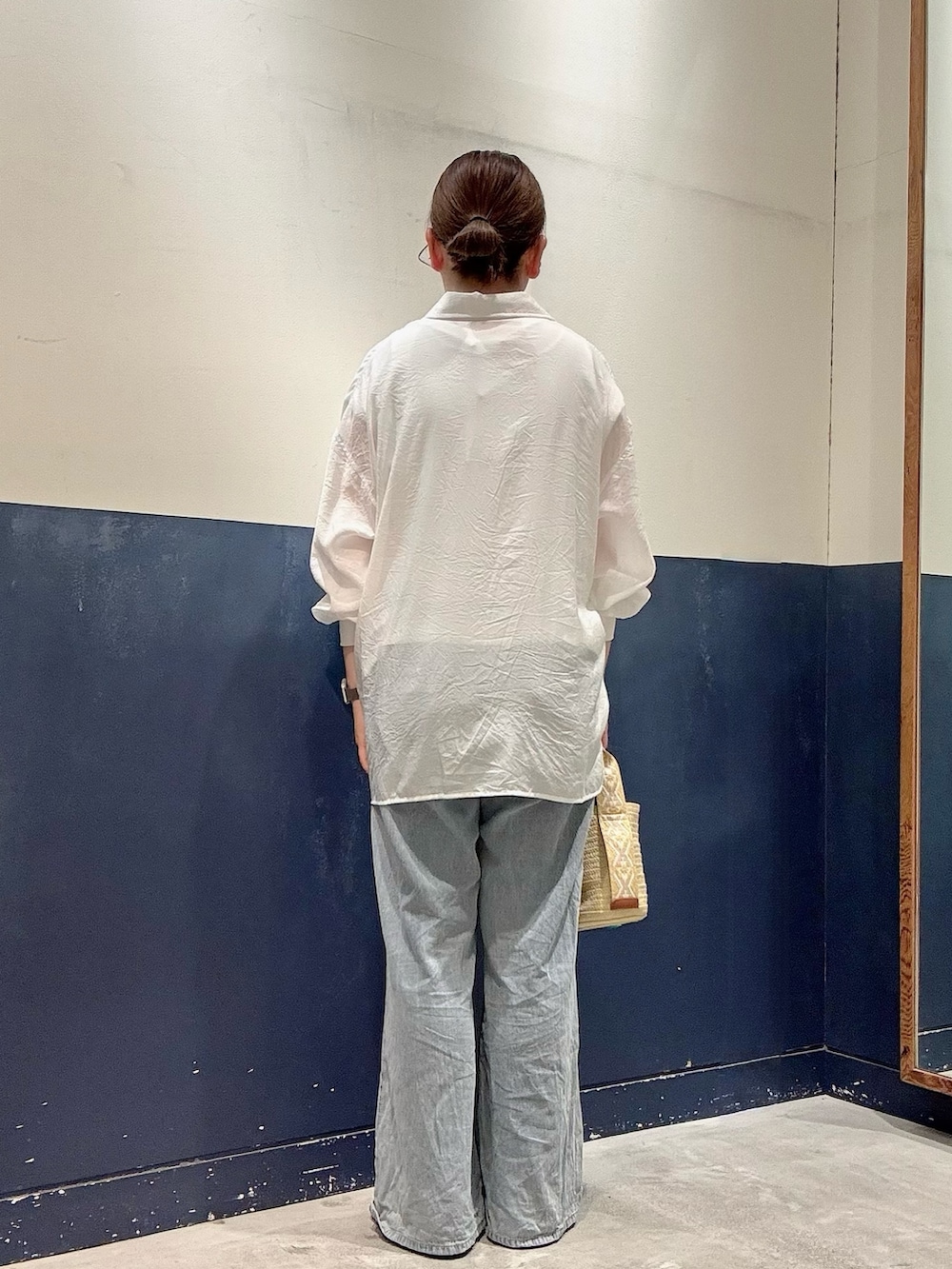 ブラック系のパンプス、ベージュ系のトートバッグ、ブルー系のデニムパンツを着用したレディースの夏コーディネートの3枚目の写真