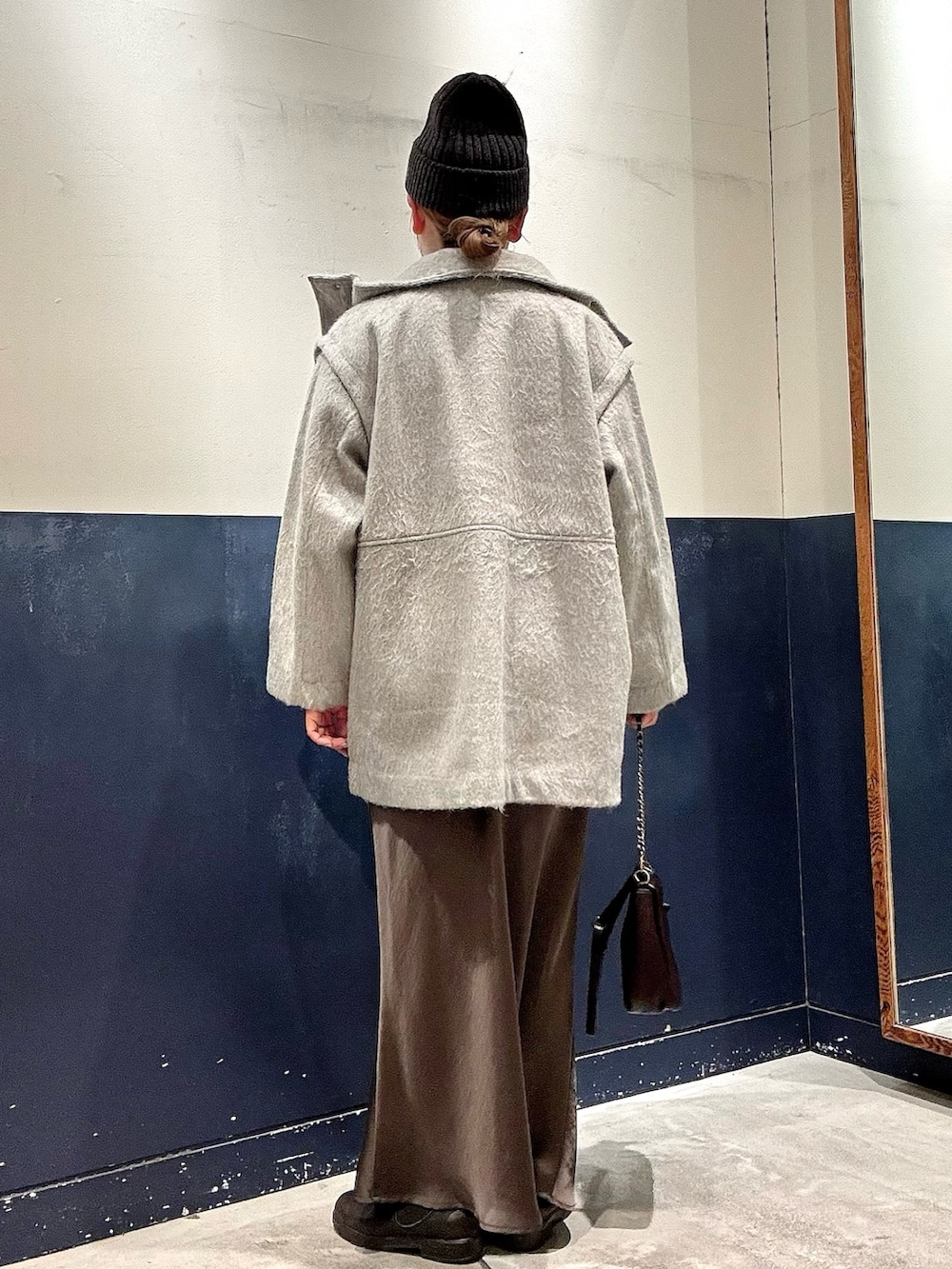 ブラック系のニット/セーター、ブラウン系のショルダーバッグ、グレー系のスカートを着用したレディースの冬コーディネートの3枚目の写真