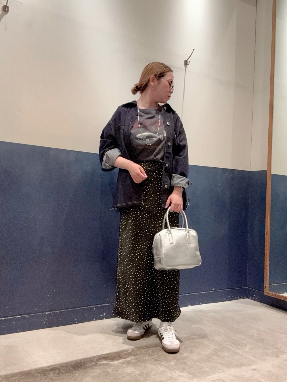 ブラック系のスカート、シルバー系のボストンバッグ、ブルー系のデニムジャケットを着用したレディースの春コーディネートの2枚目の写真