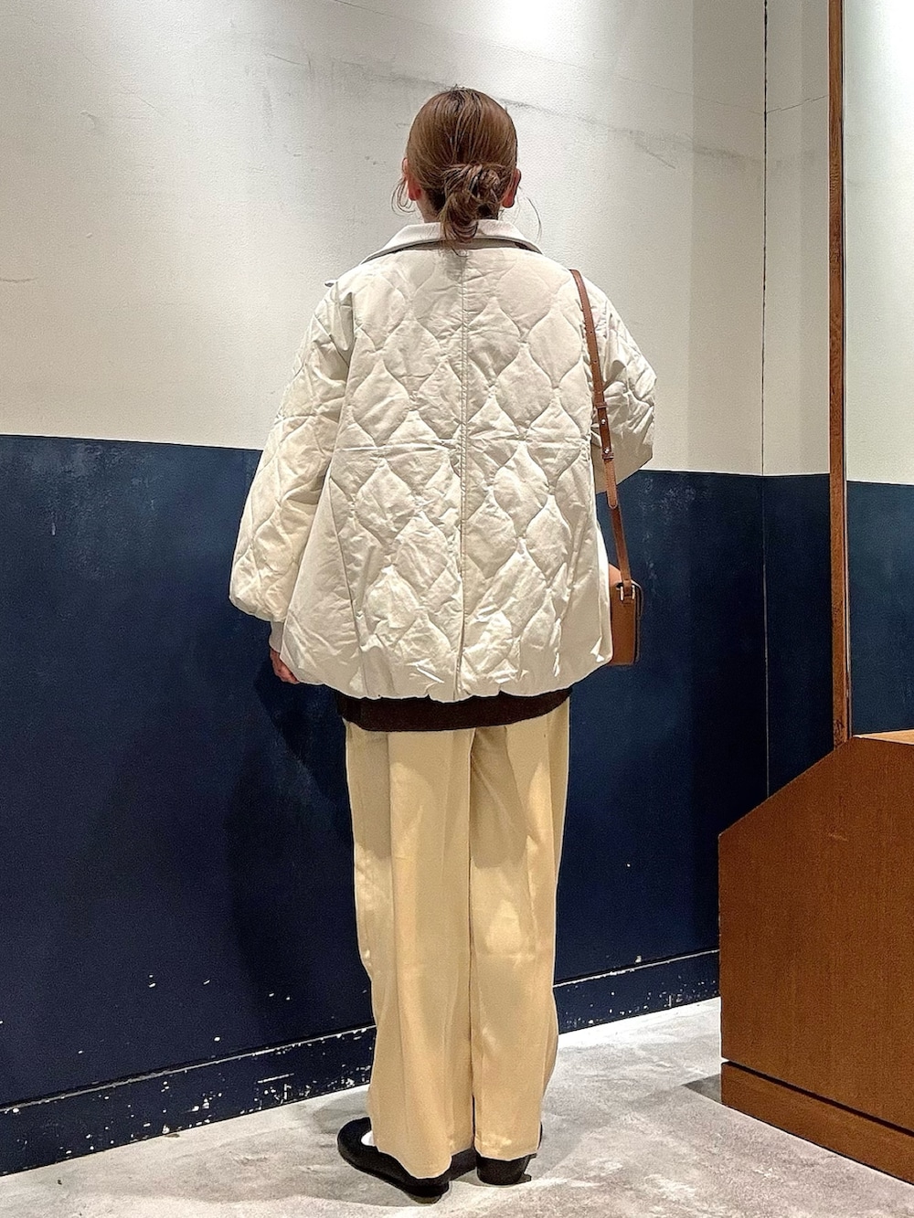 ホワイト系のブルゾン、ブラウン系のニット/セーター、イエロー系のショルダーバッグを着用したレディースの冬コーディネートの3枚目の写真