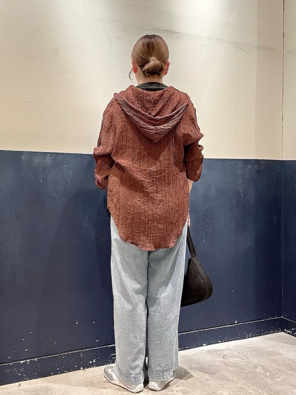 シルバー系のスニーカー、ブラック系のショルダーバッグ、ブルー系のデニムパンツを着用したレディースの春コーディネートの3枚目の写真