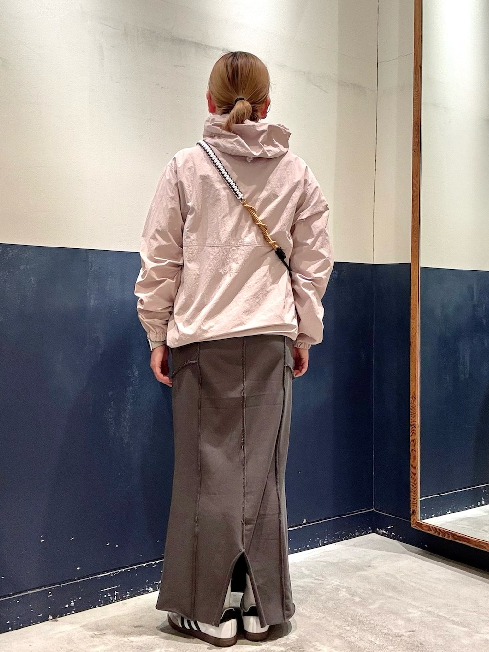 グレー系のスカート、ブラウン系のショルダーバッグ、ピンク系のマウンテンパーカーを着用したレディースの春コーディネートの3枚目の写真