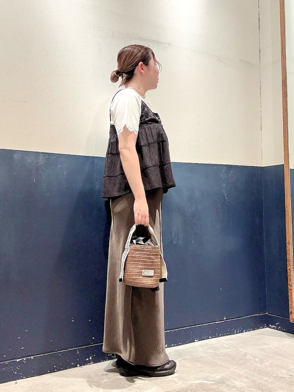 グレー系のスカート、ブラウン系のトートバッグ、ブラック系のシャツ/ブラウスを着用したレディースの夏コーディネートの2枚目の写真