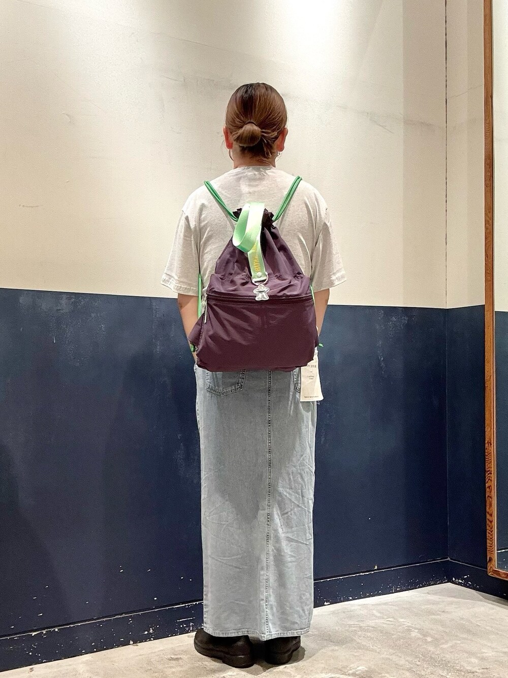 ブルー系のスカート、グレー系のTシャツ/カットソー、パープル系のバックパック/リュックを着用したレディースの夏コーディネートの3枚目の写真