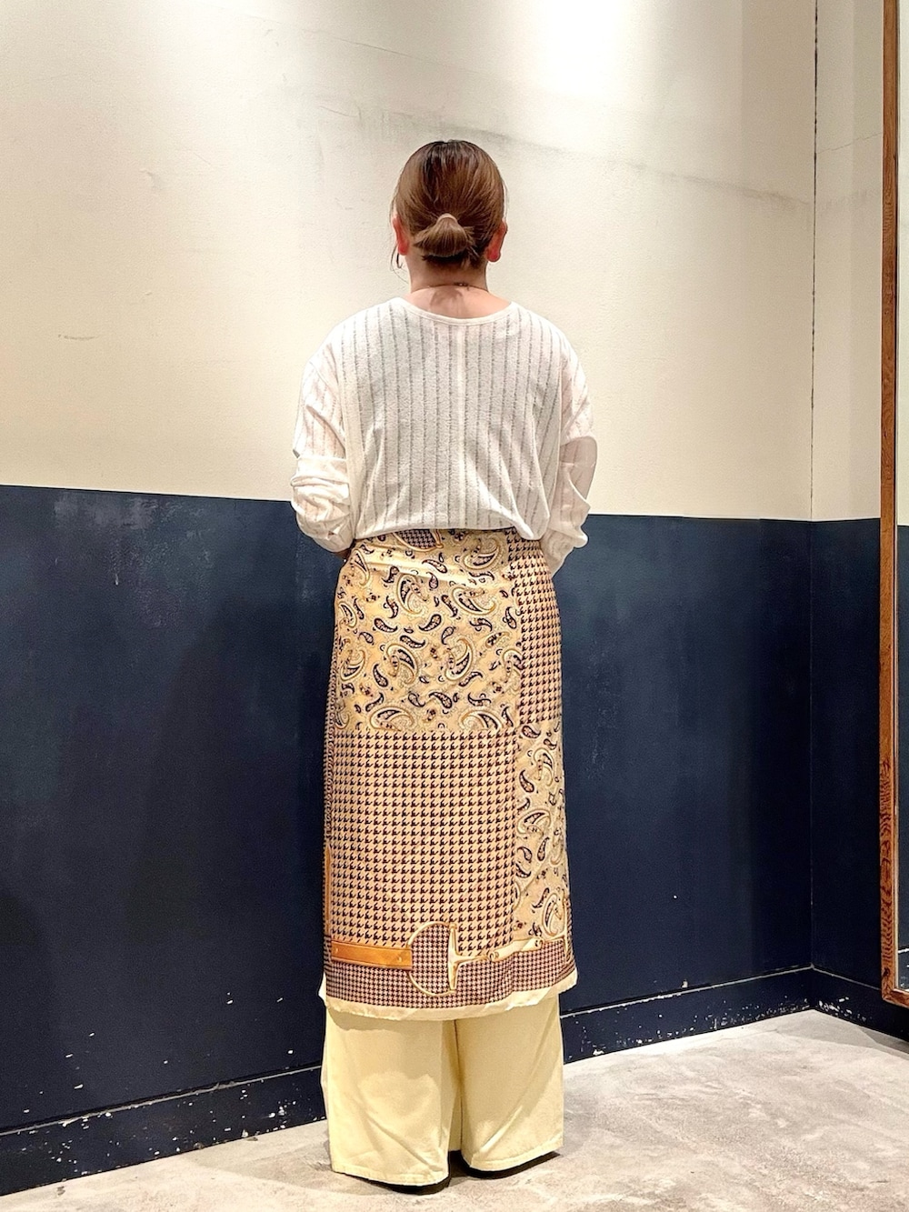 イエロー系のデニムパンツ、ブラック系のパンプス、ベージュ系のタンクトップを着用したレディースの春コーディネートの3枚目の写真