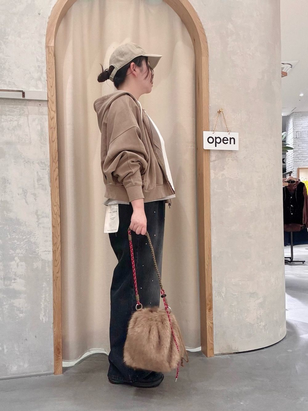 ベージュ系のパーカー、ブラウン系のトートバッグ、ブラック系のデニムパンツを着用したレディースの秋コーディネートの2枚目の写真