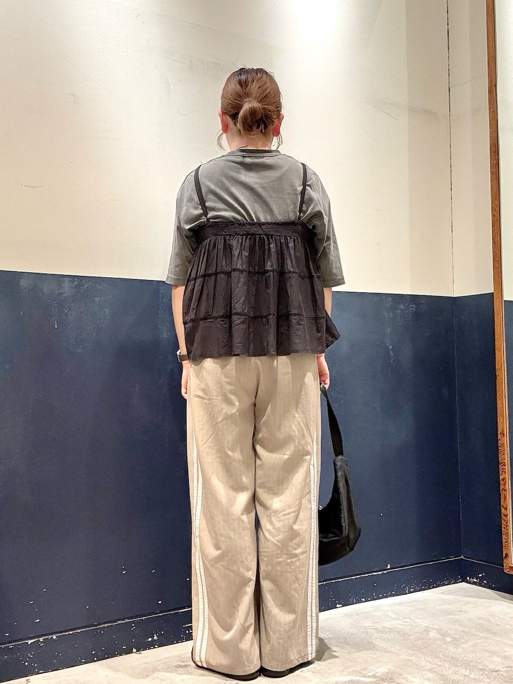 ブラック系のショルダーバッグ、ベージュ系のスラックス、ブラック系のTシャツ/カットソーを着用したレディースの夏コーディネートの3枚目の写真