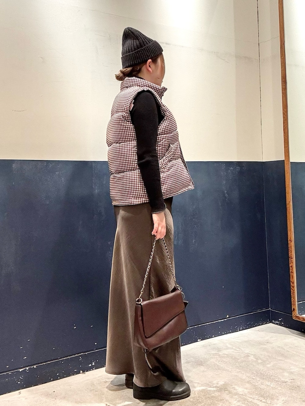 ブラウン系のショルダーバッグ、グレー系のスカート、ブラック系のニット/セーターを着用したレディースの冬コーディネートの2枚目の写真