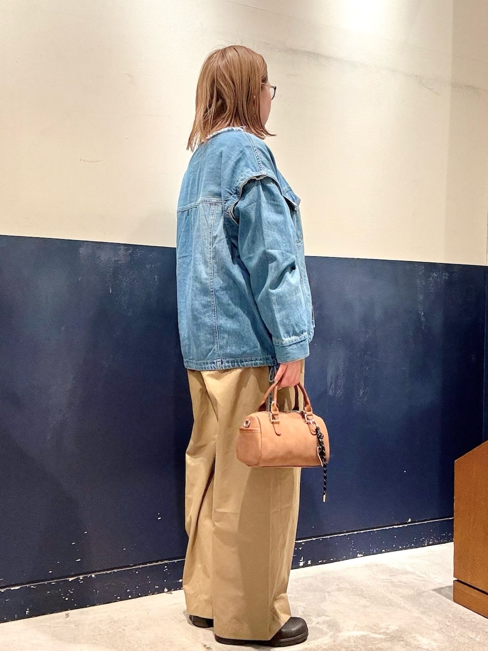 ベージュ系のショルダーバッグ、ブルー系のデニムジャケット、ベージュ系のデニムパンツを着用したレディースの冬コーディネートの2枚目の写真