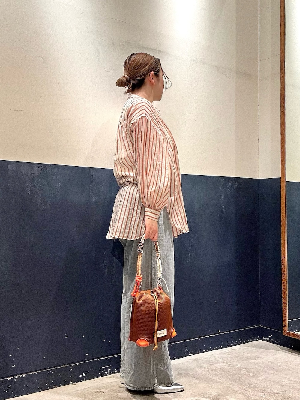 イエロー系のショルダーバッグ、ブルー系のデニムパンツ、ホワイト系のタンクトップを着用したレディースの夏コーディネートの2枚目の写真