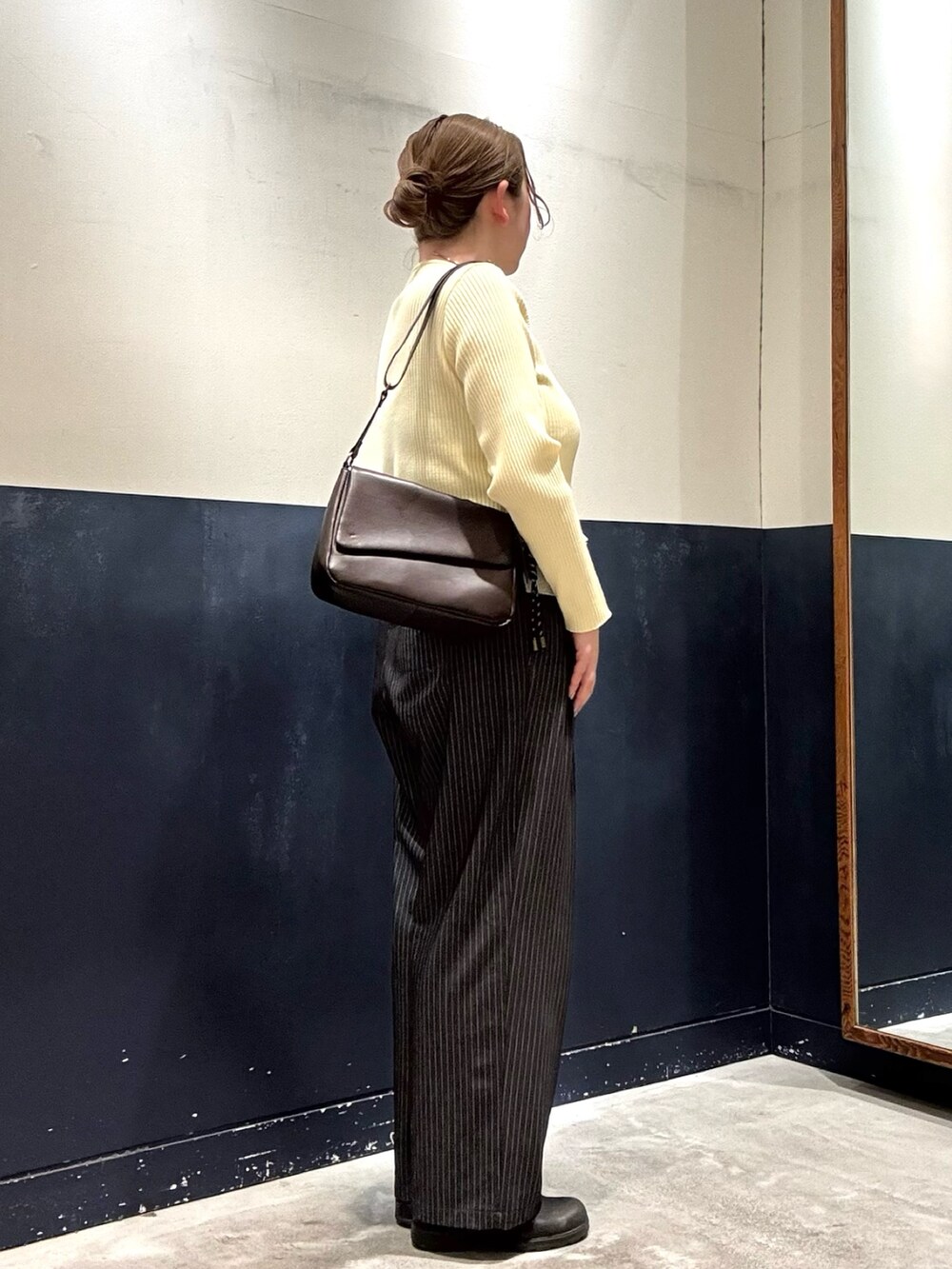 グレー系のスラックス、ブラウン系のショルダーバッグ、イエロー系のカーディガン/ボレロを着用したレディースの冬コーディネートの2枚目の写真