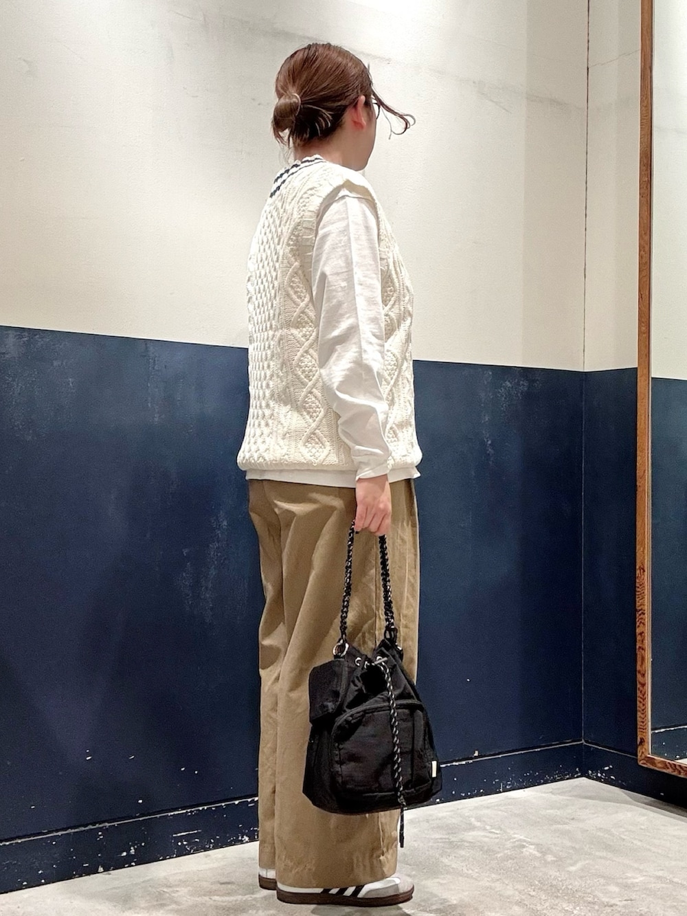 ベージュ系のデニムパンツ、ブラック系のトートバッグ、ホワイト系のベストを着用したレディースの秋コーディネートの2枚目の写真