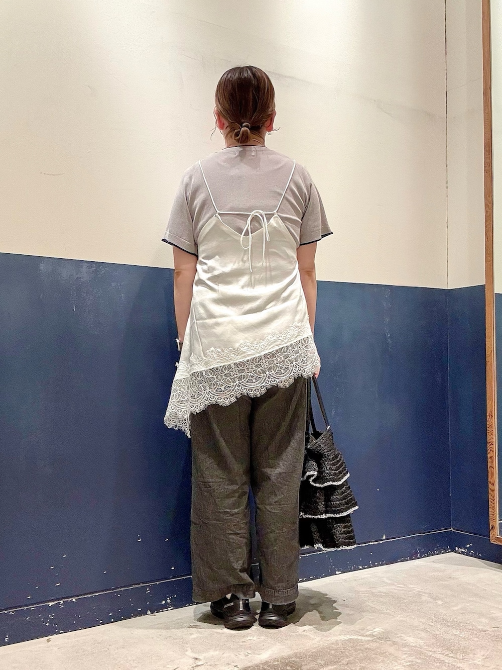 ブラック系のデニムパンツ、ブラック系のトートバッグ、ホワイト系のチュニックを着用したレディースの夏コーディネートの3枚目の写真