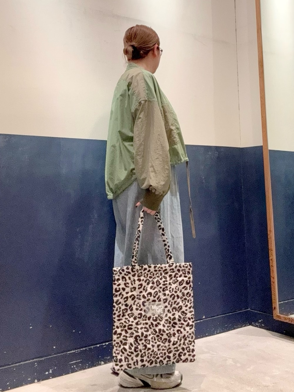 グリーン系のブルゾン、ブルー系のデニムパンツ、ホワイト系のトートバッグを着用したレディースの秋コーディネートの2枚目の写真