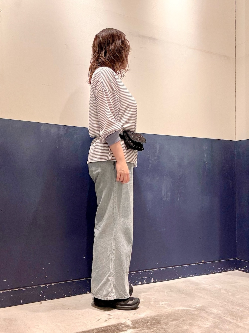 ブルー系のデニムパンツ、ブラック系のボディバッグ/ウエストポーチ、ブルー系のTシャツ/カットソーを着用したレディースの夏コーディネートの2枚目の写真