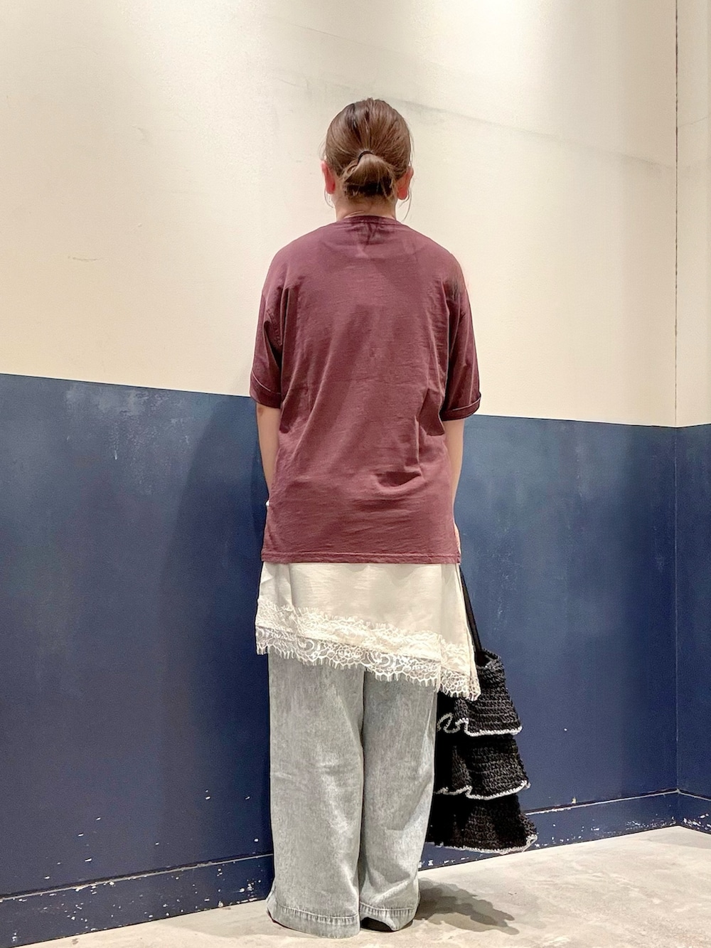 ブラック系のトートバッグ、ブルー系のデニムパンツ、ホワイト系のスカートを着用したレディースの夏コーディネートの3枚目の写真