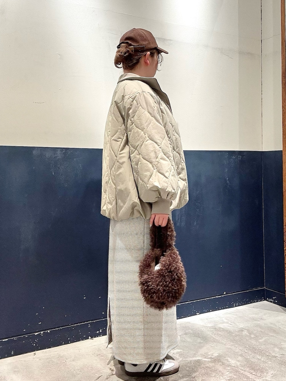 ブラウン系のトートバッグ、グリーン系のブルゾン、ホワイト系のワンピースを着用したレディースの冬コーディネートの2枚目の写真