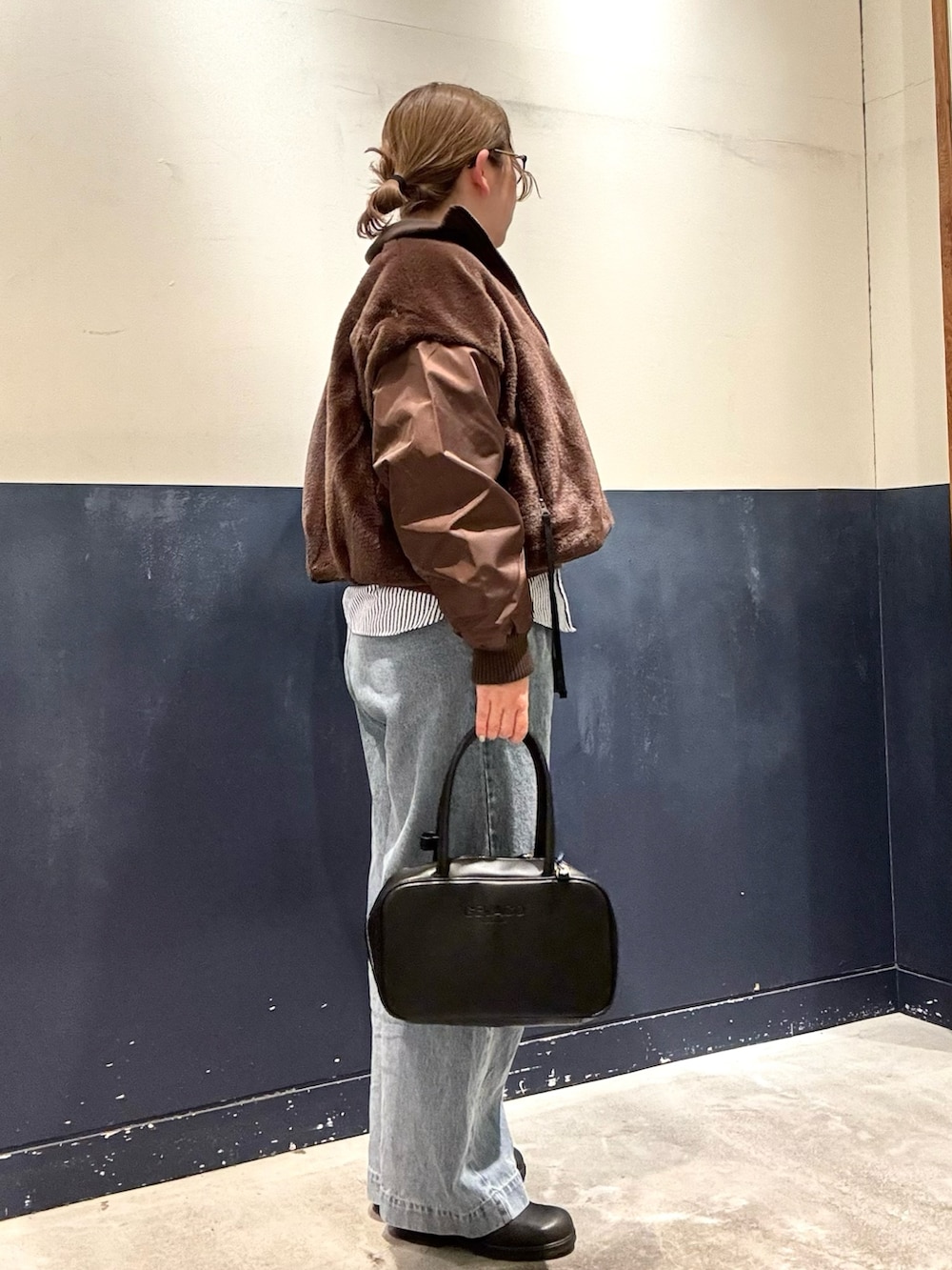 ブルー系のデニムパンツ、ブラック系のボストンバッグ、ブラウン系のブルゾンを着用したレディースの冬コーディネートの2枚目の写真