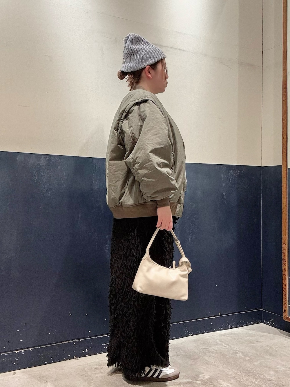 グリーン系のMA-1、グレー系のニット/セーター、ブラック系のスカートを着用したレディースの冬コーディネートの2枚目の写真