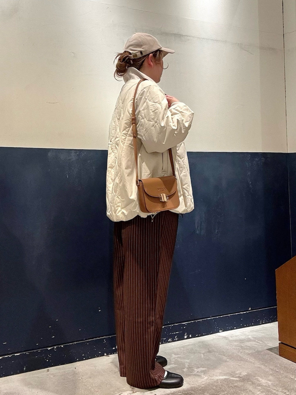 ホワイト系のブルゾン、ブラウン系のスラックス、イエロー系のショルダーバッグを着用したレディースの冬コーディネートの2枚目の写真