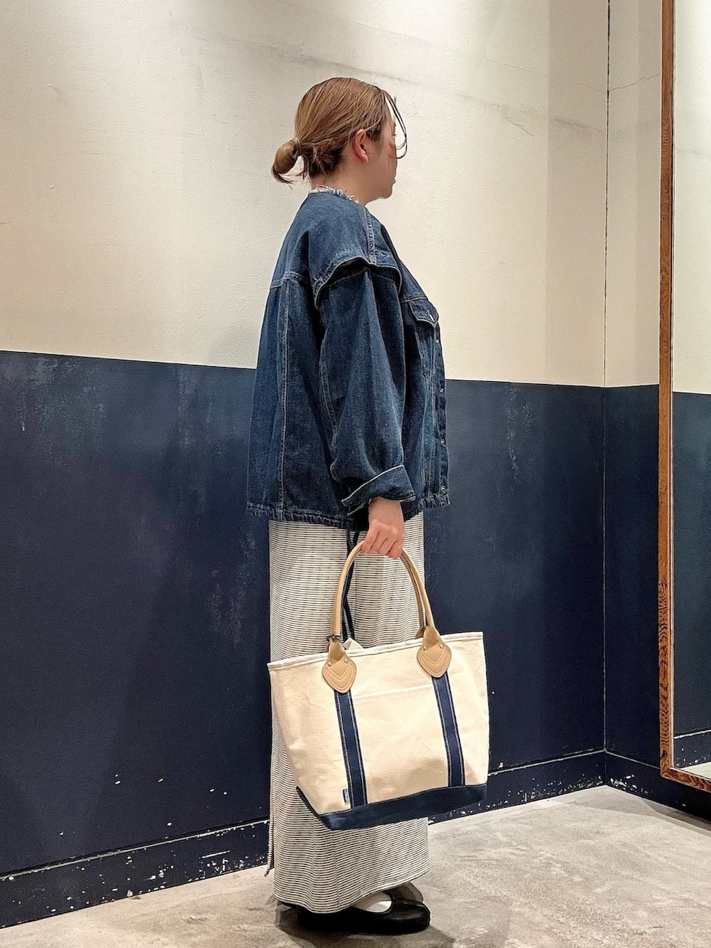 ブルー系のトートバッグ、ブルー系のデニムジャケット、ホワイト系のワンピースを着用したレディースの春コーディネートの2枚目の写真