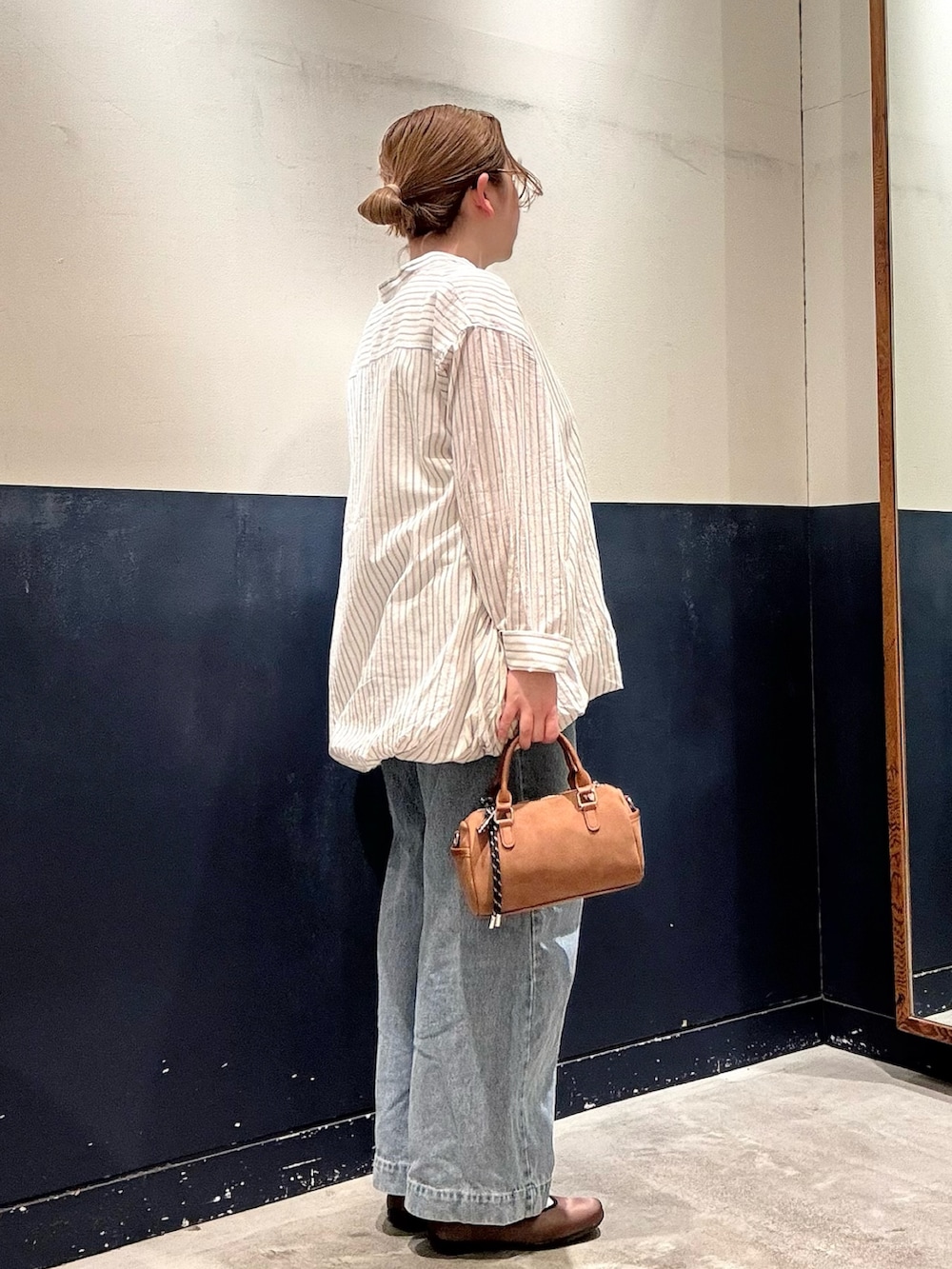 ブルー系のデニムパンツ、ベージュ系のショルダーバッグ、ホワイト系のシャツ/ブラウスを着用したレディースの春コーディネートの2枚目の写真