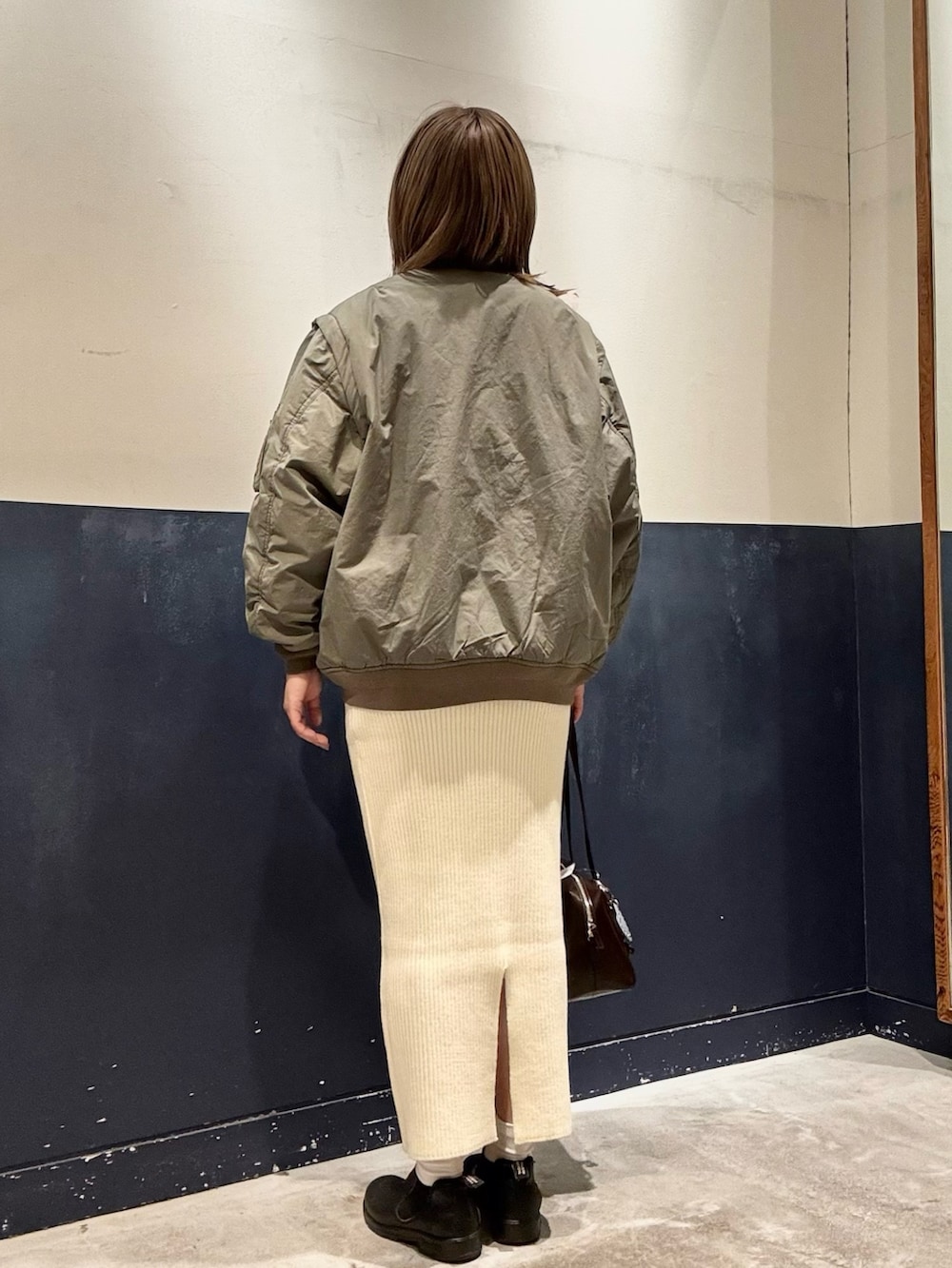 ホワイト系のスカート、ブラウン系のトートバッグ、ホワイト系のニット/セーターを着用したレディースの冬コーディネートの3枚目の写真