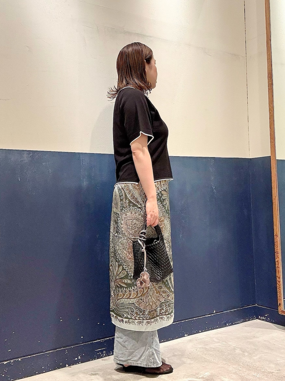 ブラック系のパンプス、ブラック系のショルダーバッグ、ブルー系のデニムパンツを着用したレディースの夏コーディネートの2枚目の写真