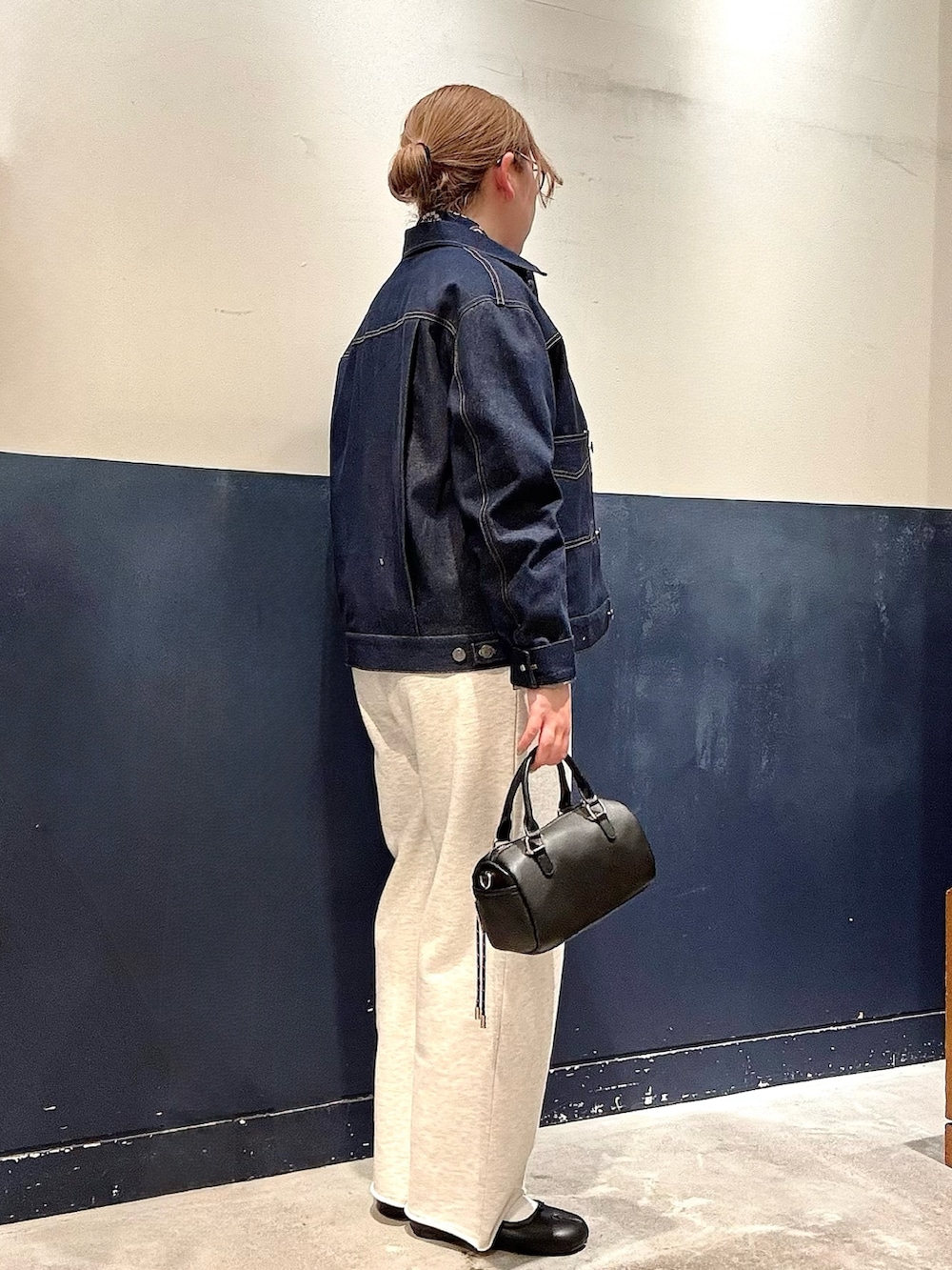 ブルー系のブルゾン、ブラック系のショルダーバッグ、ホワイト系のスウェットパンツを着用したレディースの冬コーディネートの2枚目の写真