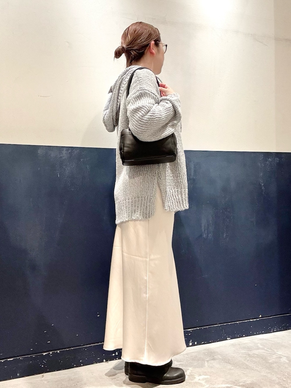 ブラック系のトートバッグ、ブルー系のニット/セーター、ホワイト系のTシャツ/カットソーを着用したレディースの秋コーディネートの2枚目の写真