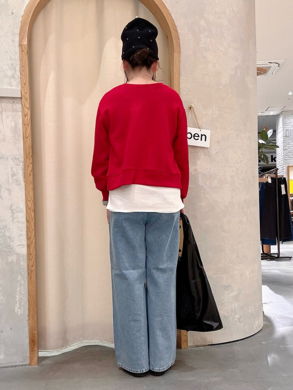 ブラック系のトートバッグ、ブルー系のデニムパンツ、レッド系のカーディガン/ボレロを着用したレディースの秋コーディネートの3枚目の写真