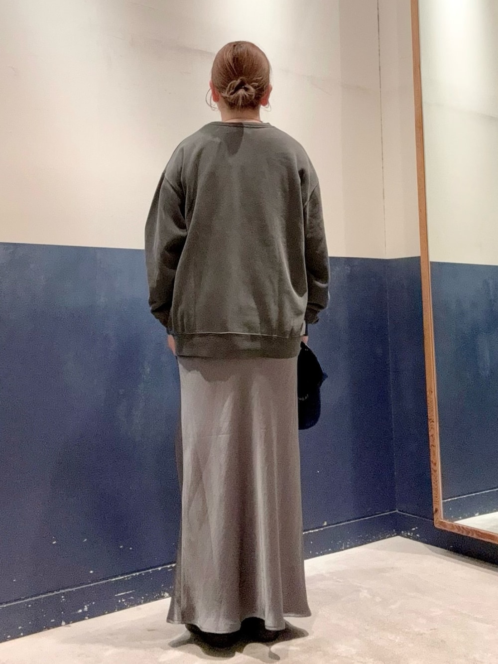 グレー系のスカート、ホワイト系のTシャツ/カットソー、ブラック系のスウェットを着用したレディースの秋コーディネートの3枚目の写真