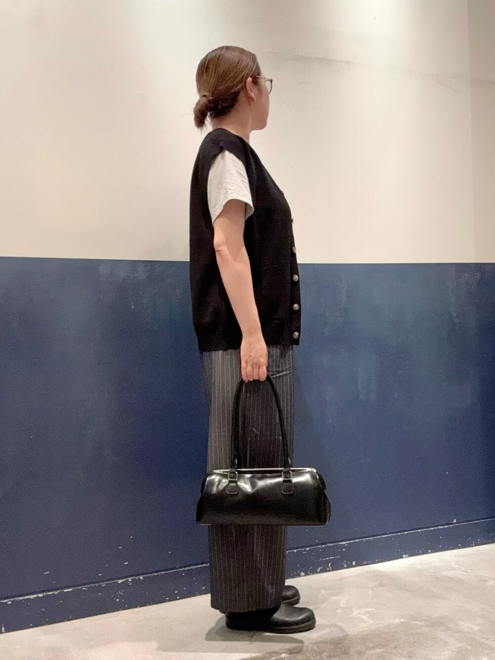 ブラック系のニット/セーター、グレー系のスラックス、グレー系のTシャツ/カットソーを着用したレディースの夏コーディネートの2枚目の写真