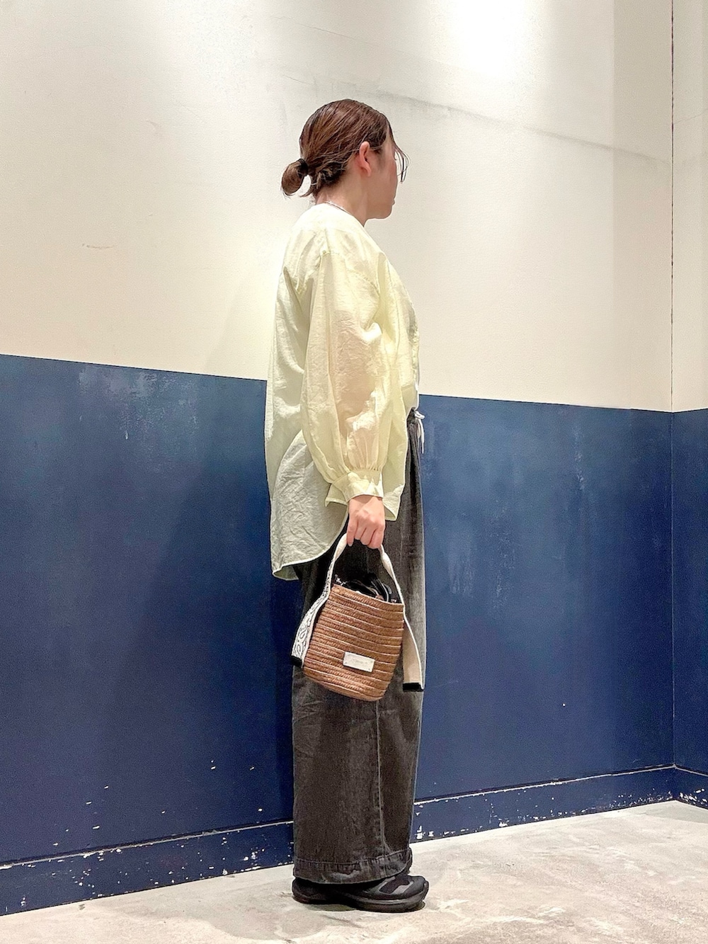 ブラウン系のトートバッグ、ブラック系のデニムパンツ、ホワイト系のTシャツ/カットソーを着用したレディースの夏コーディネートの2枚目の写真