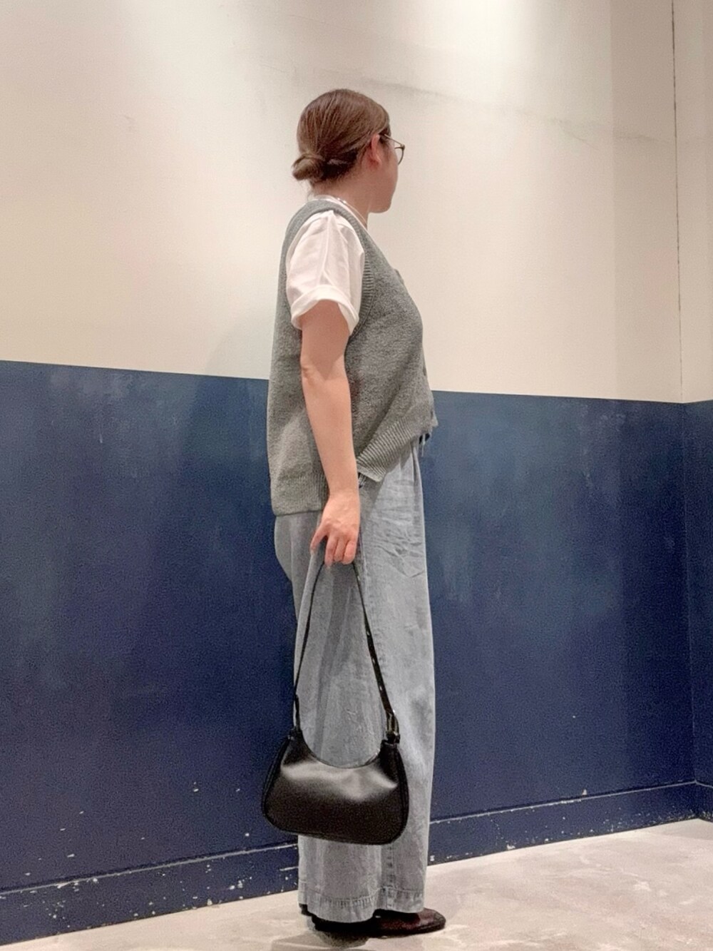 ブラック系のトートバッグ、ブルー系のデニムパンツ、グレー系のベストを着用したレディースの夏コーディネートの2枚目の写真