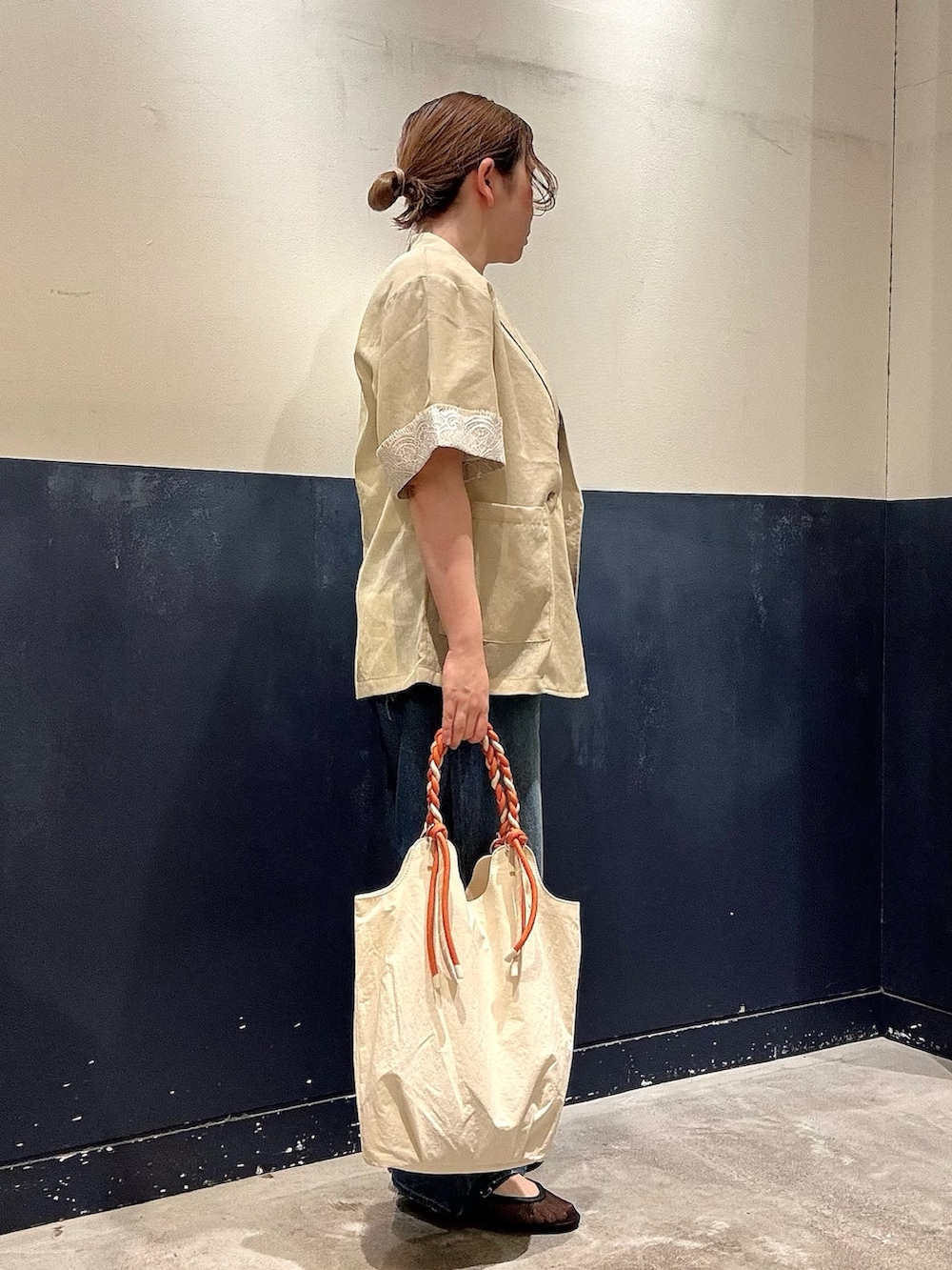 ブラック系のパンプス、ホワイト系のトートバッグ、ブルー系のデニムパンツを着用したレディースの春コーディネートの2枚目の写真