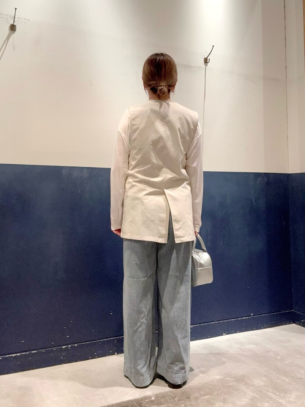 シルバー系のショルダーバッグ、ベージュ系のベスト、ホワイト系のTシャツ/カットソーを着用したレディースの春コーディネートの3枚目の写真
