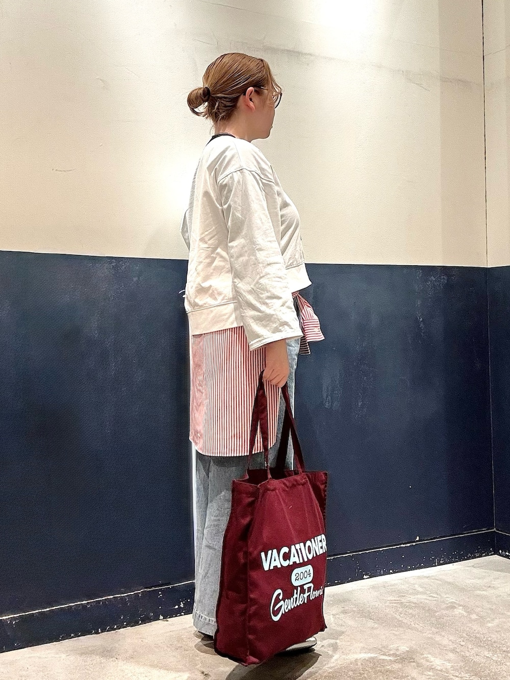 シルバー系のパンプス、ブルー系のデニムパンツ、ブラウン系のトートバッグを着用したレディースの冬コーディネートの2枚目の写真