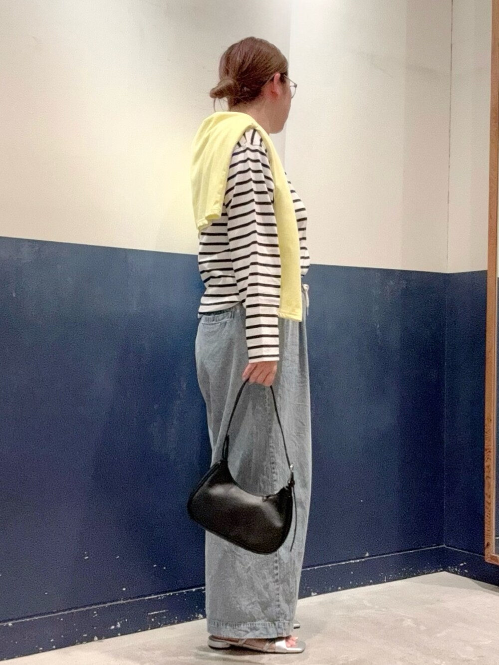 イエロー系のカーディガン/ボレロ、ブラック系のトートバッグ、ブルー系のデニムパンツを着用したレディースの夏コーディネートの2枚目の写真