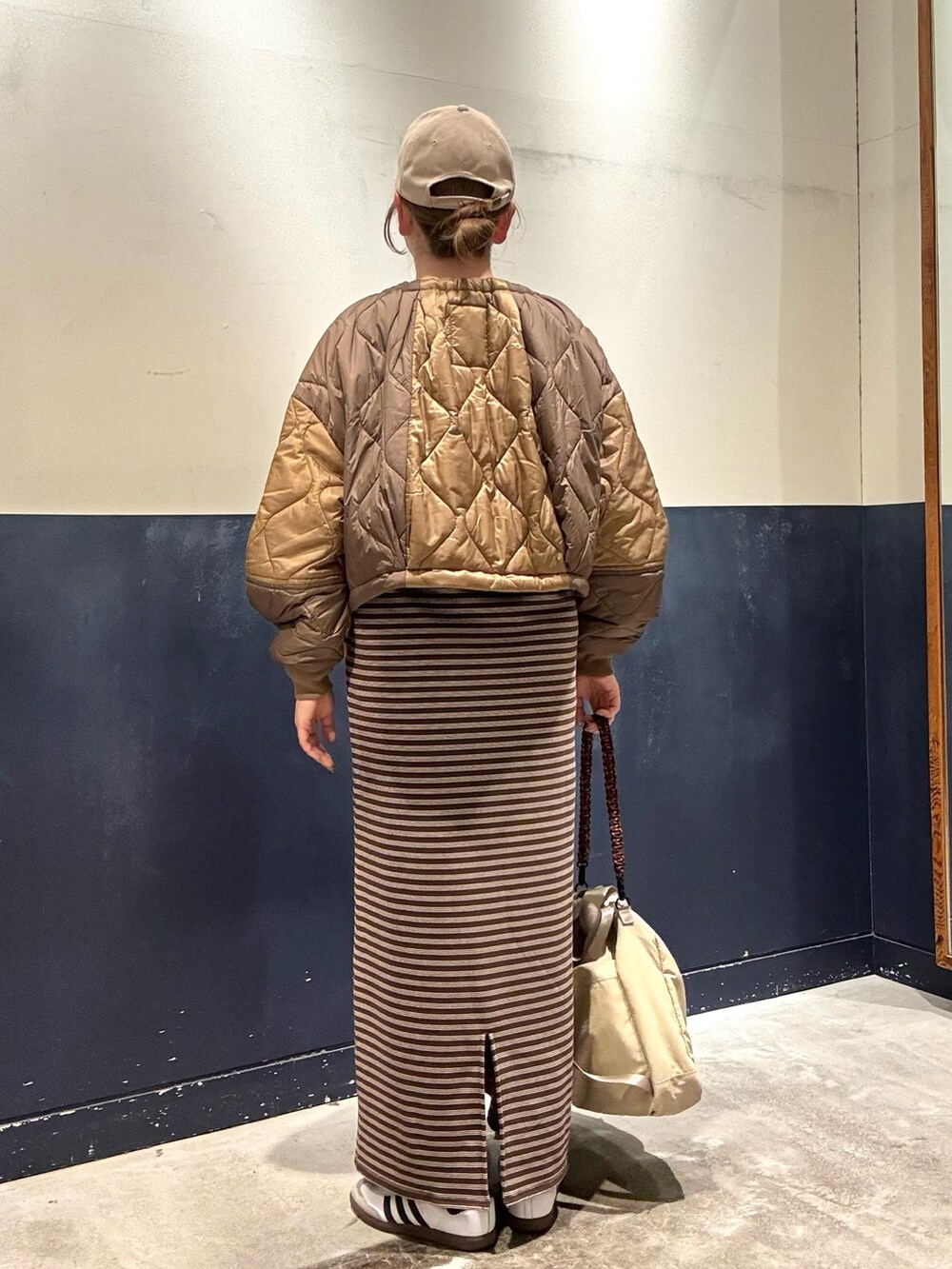 ベージュ系のトートバッグ、ブラウン系のワンピース、イエロー系のブルゾンを着用したレディースの冬コーディネートの3枚目の写真