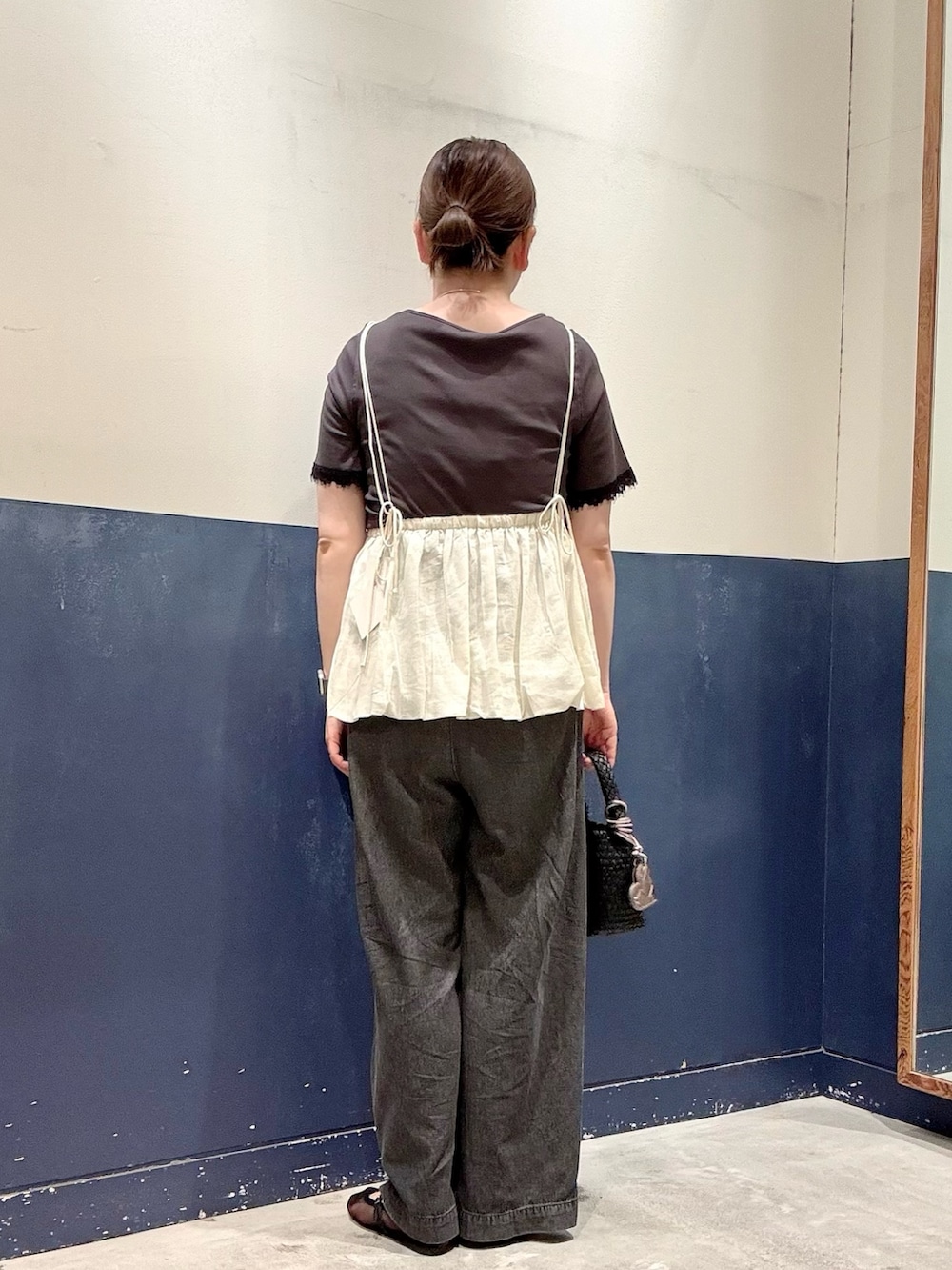 ブラック系のパンプス、ブラック系のショルダーバッグ、ブラック系のデニムパンツを着用したレディースの夏コーディネートの3枚目の写真