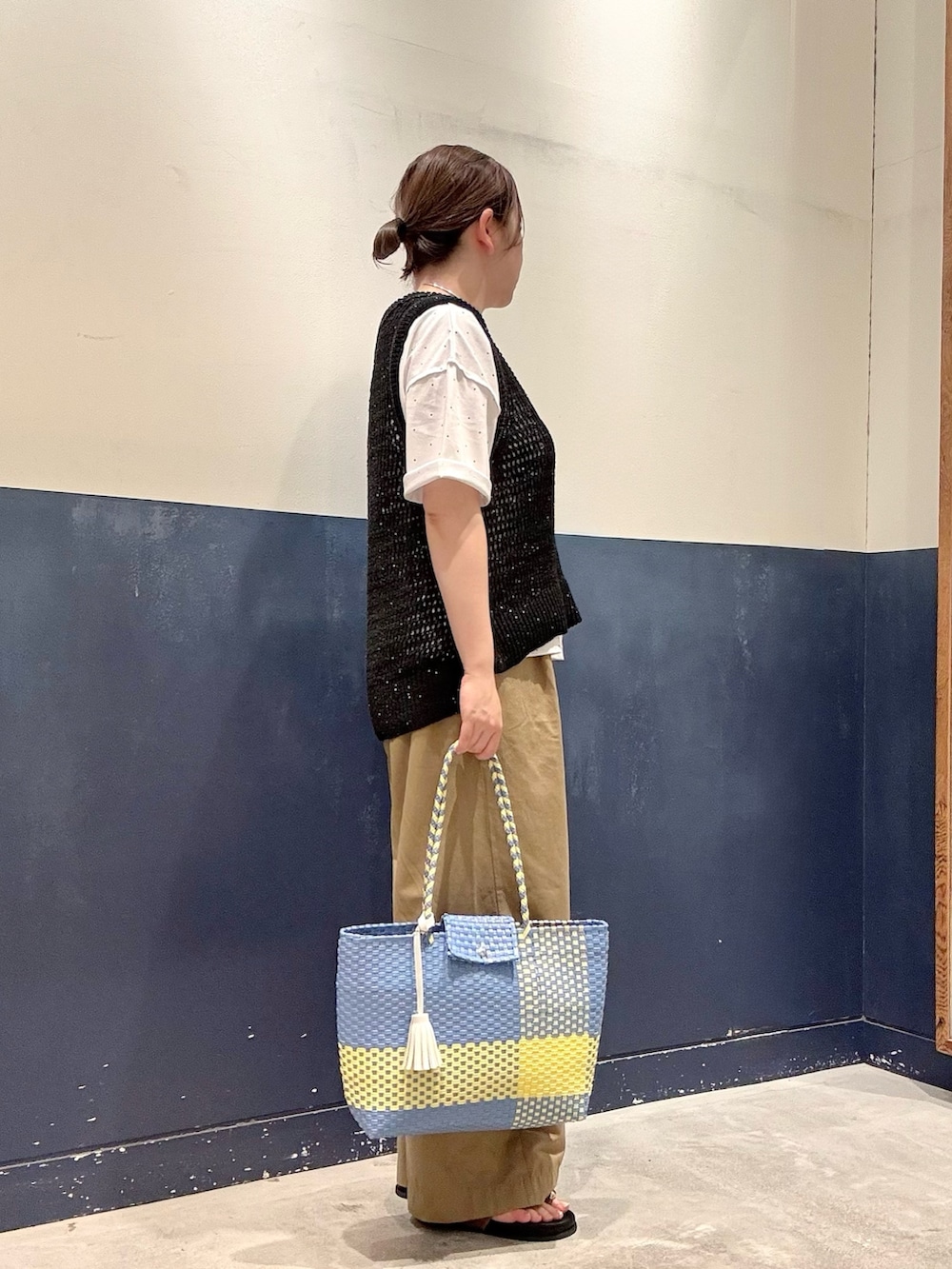 ブルー系のトートバッグ、ベージュ系のデニムパンツ、イエロー系のサンダルを着用したレディースの夏コーディネートの2枚目の写真