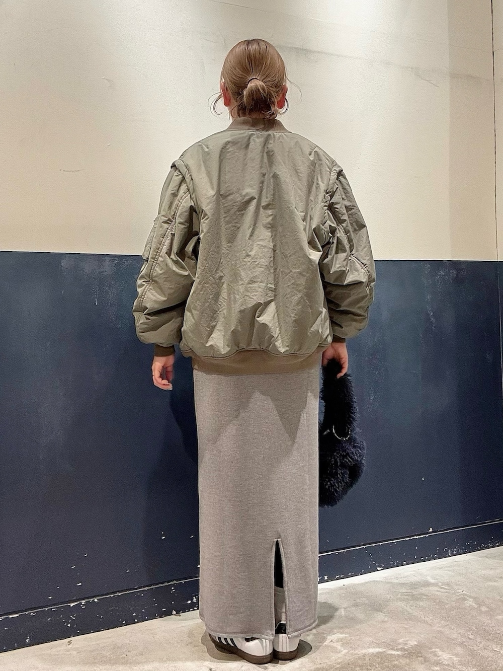 グレー系のワンピース、グリーン系のMA-1、ブルー系のトートバッグを着用したレディースの冬コーディネートの3枚目の写真