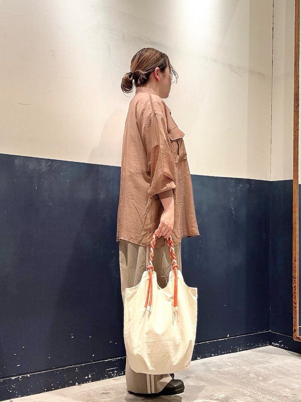 ホワイト系のトートバッグ、ベージュ系のスラックス、ホワイト系のTシャツ/カットソーを着用したレディースの夏コーディネートの2枚目の写真