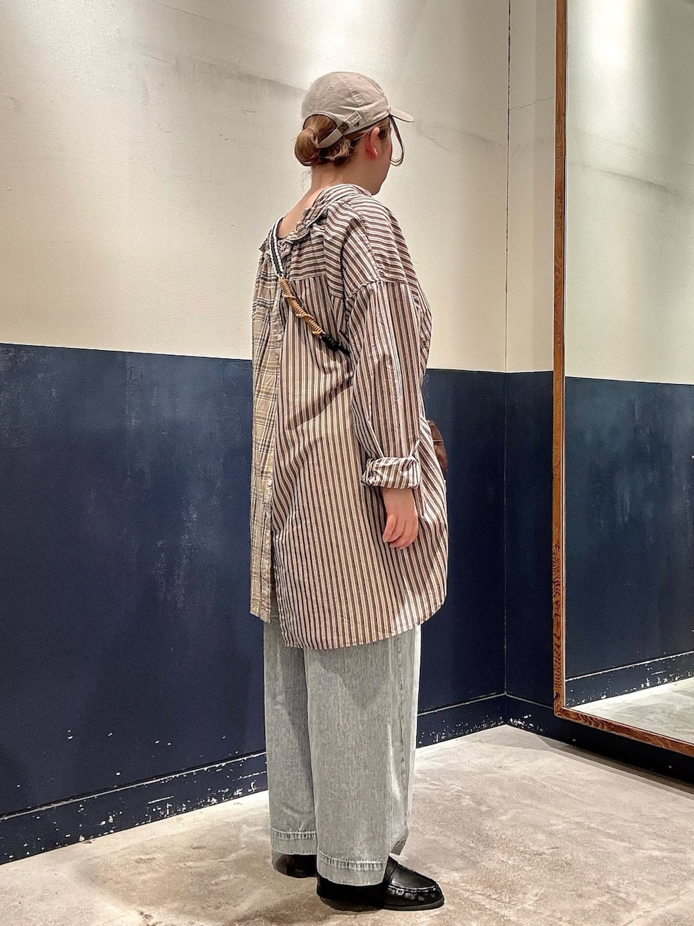 ブルー系のデニムパンツ、ブラック系のローファー、ブラウン系のスカートを着用したレディースの春コーディネートの2枚目の写真