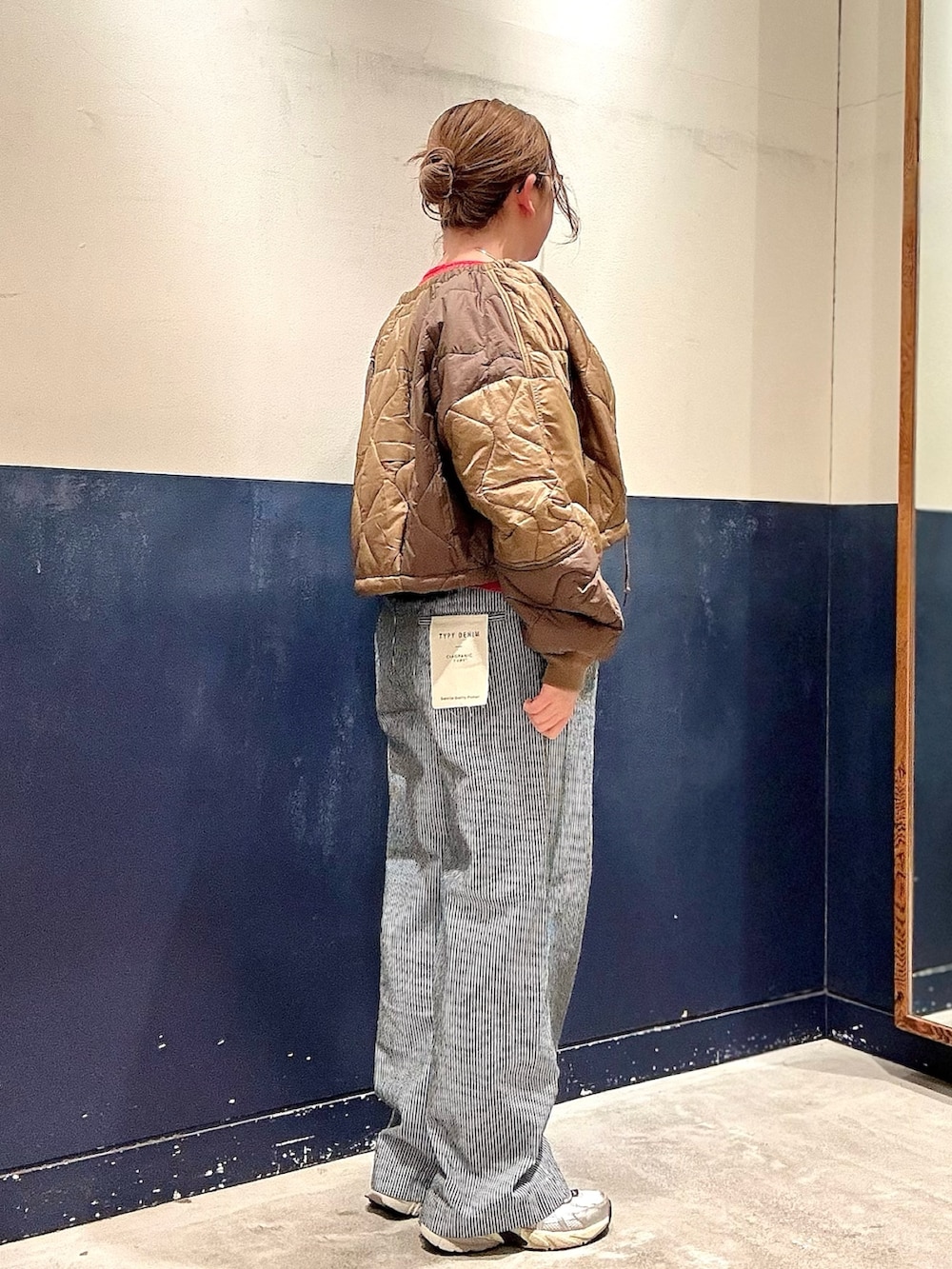 イエロー系のブルゾン、レッド系のカーディガン/ボレロ、ブルー系のデニムパンツを着用したレディースの冬コーディネートの2枚目の写真