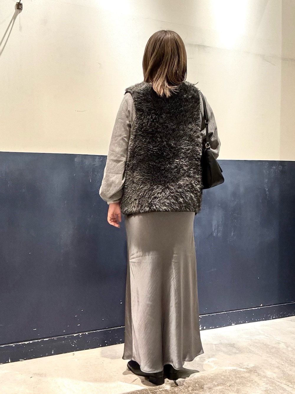 グレー系のスウェット、グレー系のスカート、ブラック系のショルダーバッグを着用したレディースの冬コーディネートの3枚目の写真